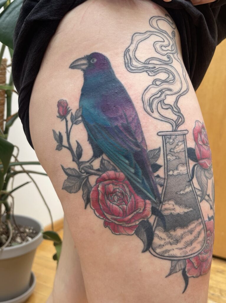 a tattoo of a raven in iridescent colors perched on a rose vine with some blooming roses, wrapping around a potion bottle full of clouds with smoke coming out of the top (the potion bottle is healed and in black and grey)